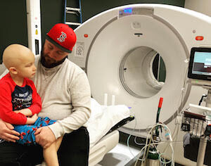 Jaxson with his dad by a large imaging machine while treating against Rhabdomyosarcoma | cCARE | Fresno & San Diego, CA