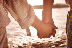 young couple holding hands on beach